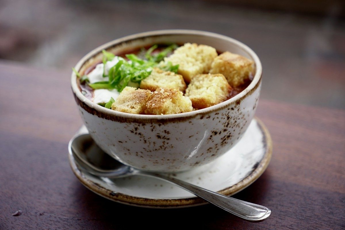 Suppe mit gerösteten Brotwürfeln und Frühlingszwiebeln in einer Keramikschale
