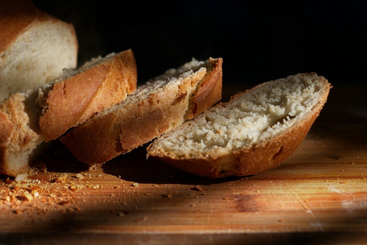 Aufgeschnittenes Brot mit kräftiger Kruste auf einem dunklen Holzbrett