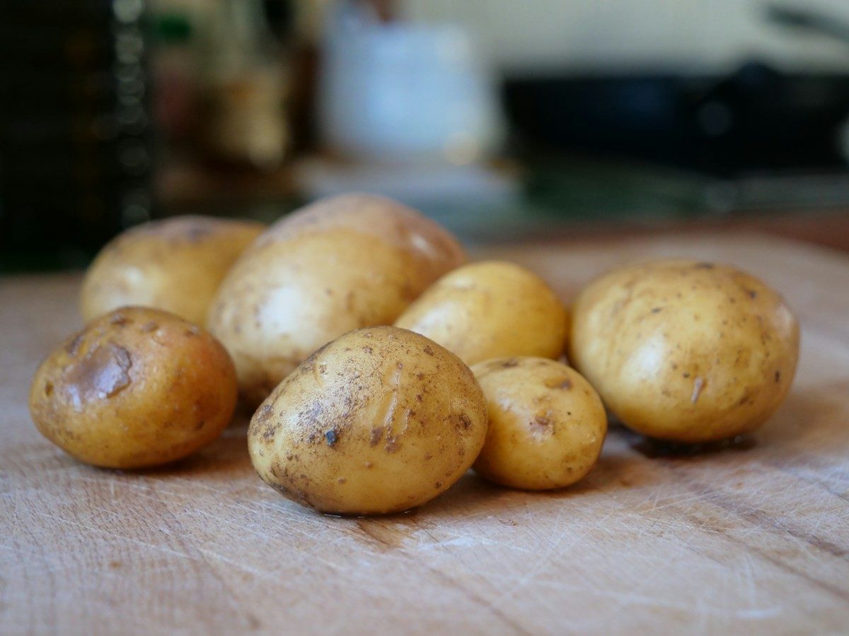 Ungeschälte Kartoffeln mit dünner, heller Schale auf einem Holzbrett