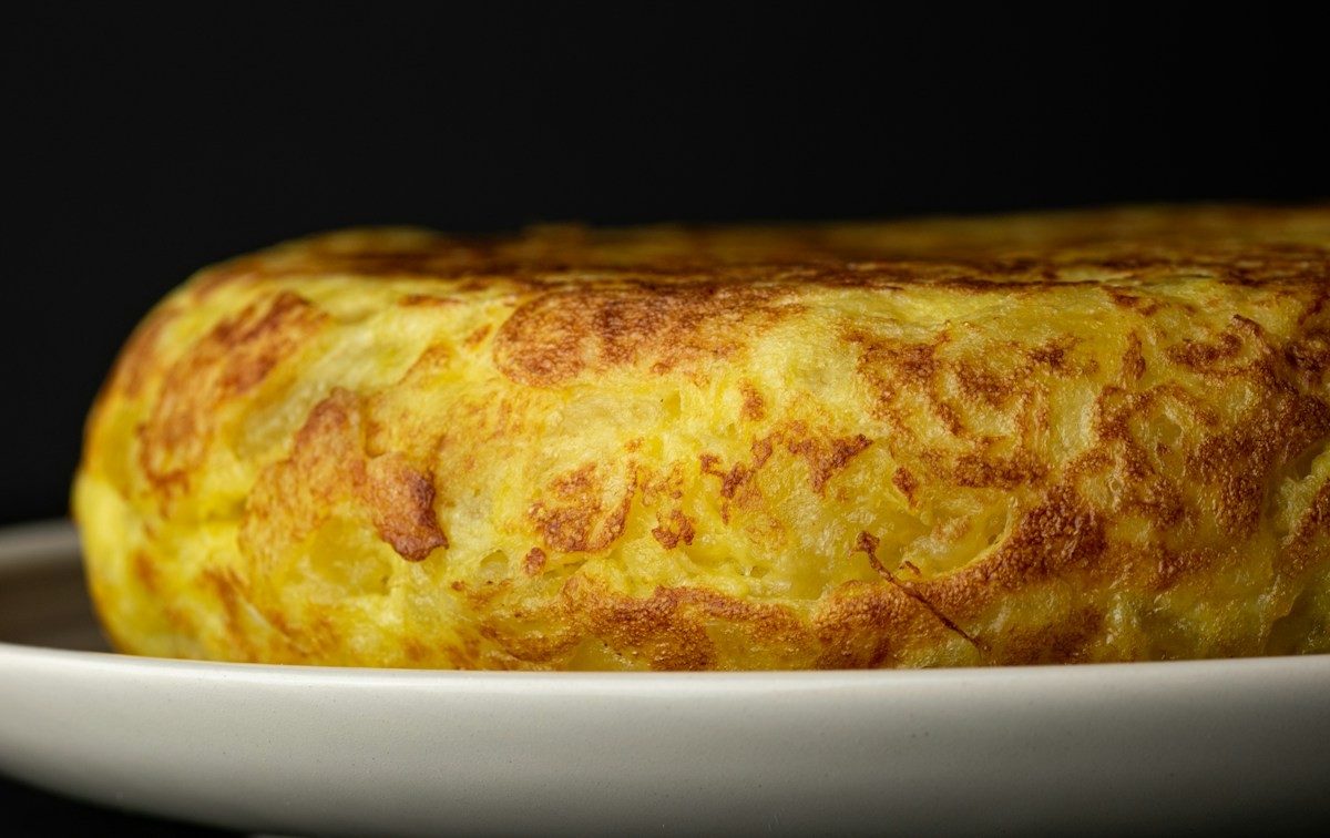 Dicke, goldbraune Kartoffeltortilla auf einem weißen Teller